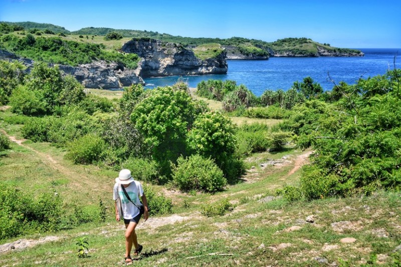 Woman walking towards camera away from grassy area and lake