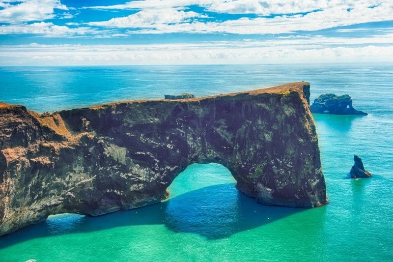 A natural arch spanning into the sea on one of the best Iceland Beaches