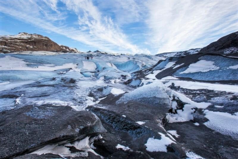 The top of a glacier with broken ice and black sand showing through