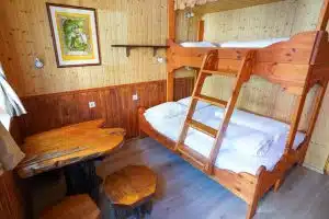 Wooden triple bunkbed with wooden table in corner