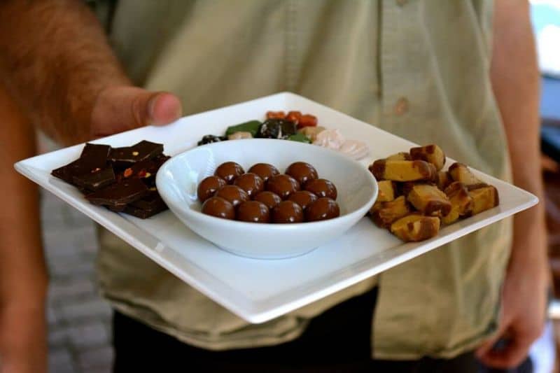 Chocolate and snacks on a white plate being held by a man