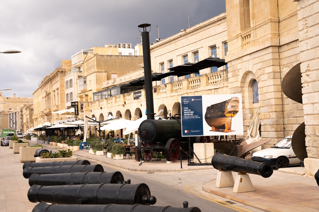 Cannons in foreground and stone buildings with parasols outside