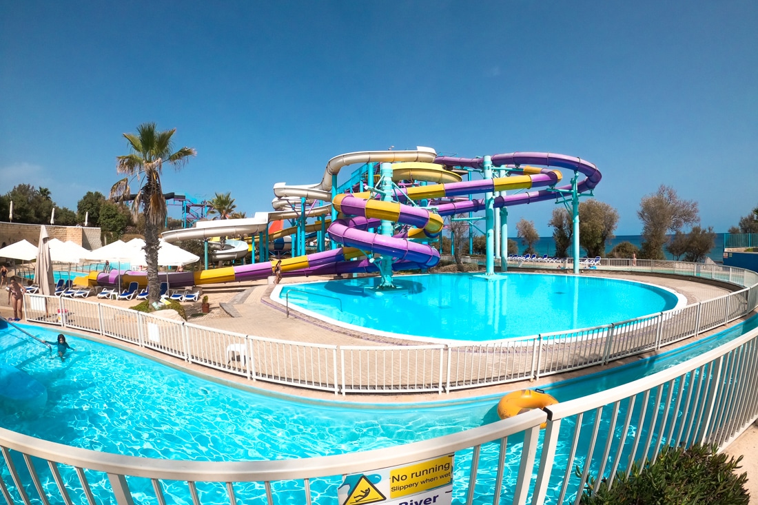 Purple and yellow water park slides and large pool underneath