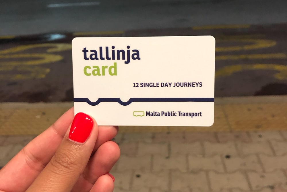 Holding a white bus card which says Tallinja card on it